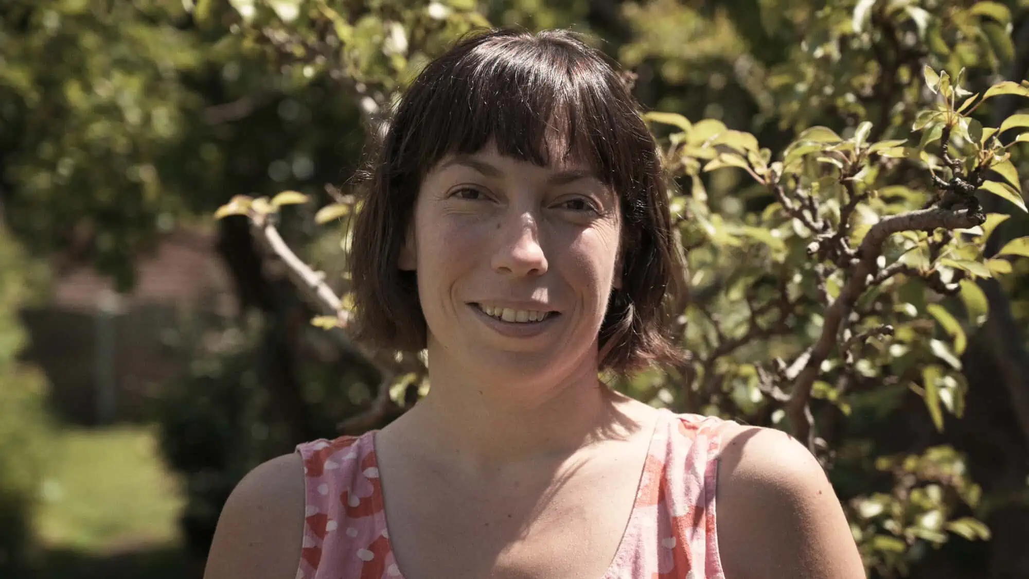 Image Description: A landscape format image. A head and shoulders portrait of Elizabeth Wright in front of an out of focus background of trees.