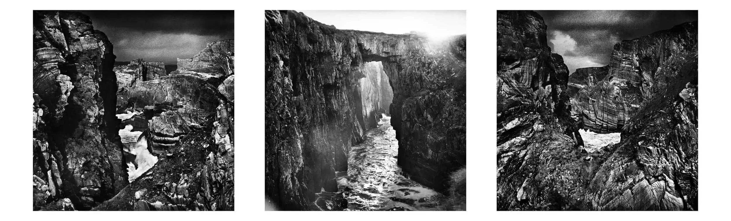 Image ID: A series of three square format black and white images. The images are grainy and have been made on film. These are images of sea cliffs through which we get glimpses of the ocean beyond. The rock is very dark with regular bright patches. …