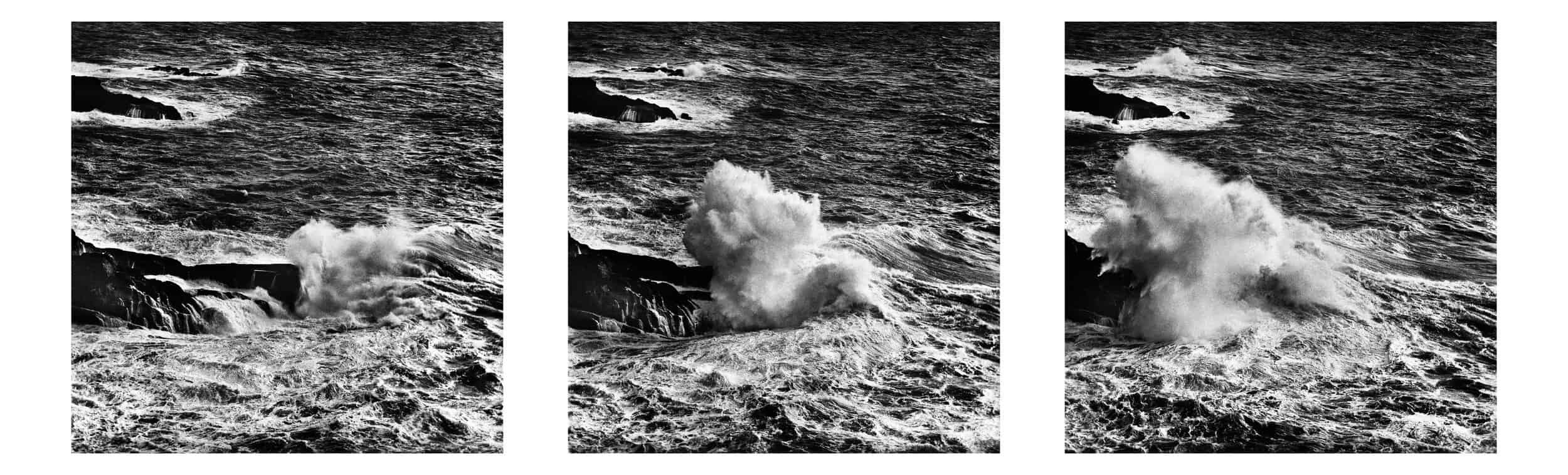 Image ID: A series of three square format black and white images. The images are grainy and have been made on film. This sequence shows the stages of a powerful wave approaching and breaking on coastal rocks. The images are very dark, but there is also bright white in the frothing ocean.