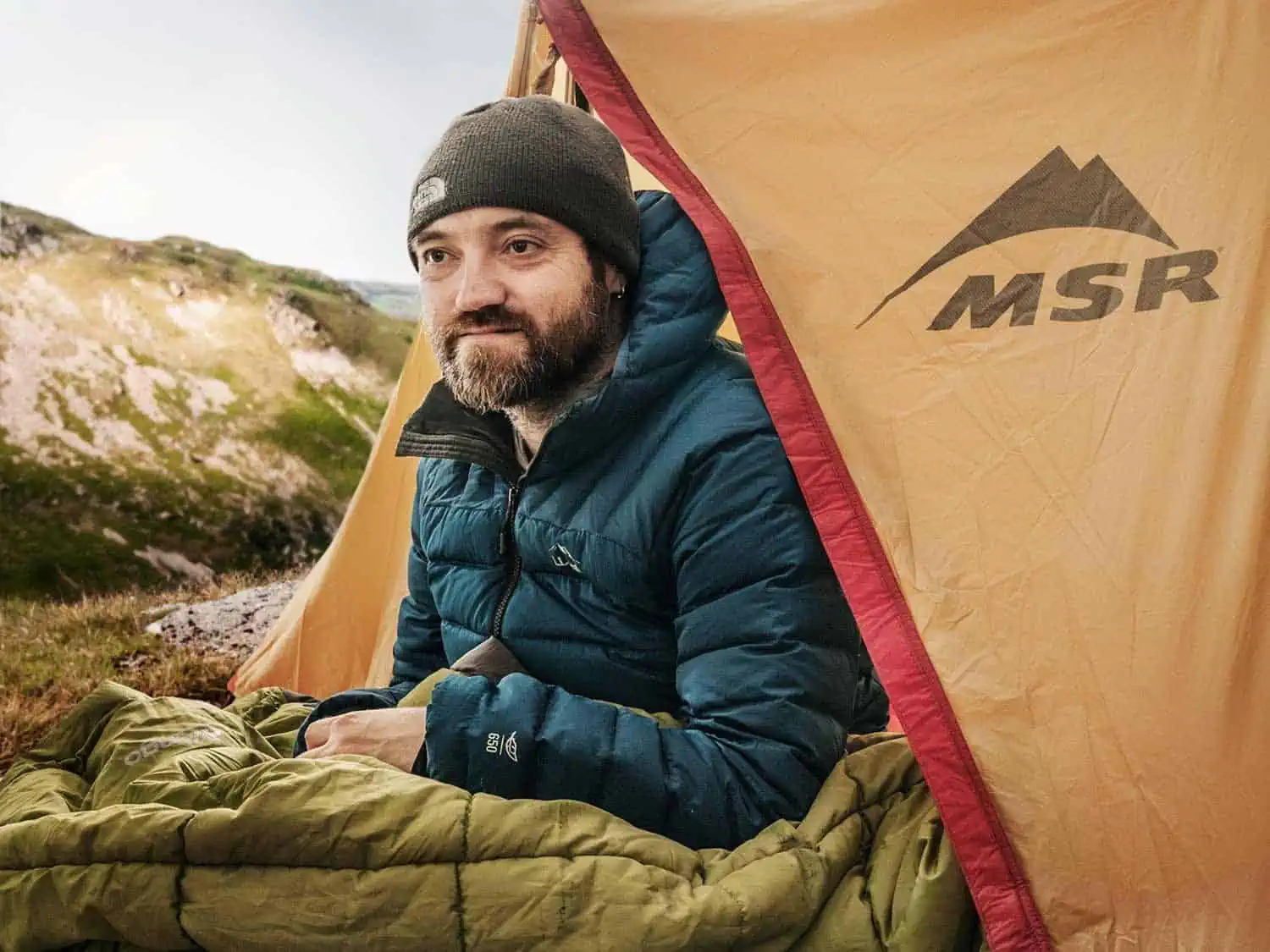 man sits in msr hubba hubba ultralightweight backpacking tent in the outdoors