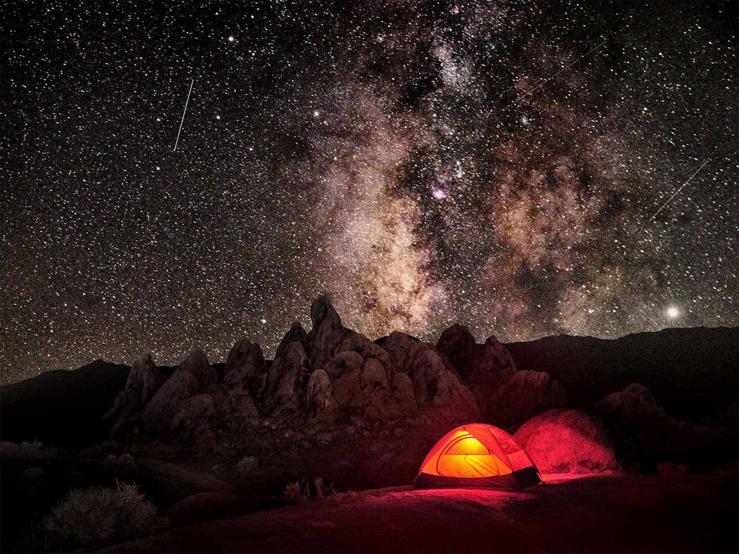 REI Half Dome 2 backpacking tent at night lit up against a starry sky